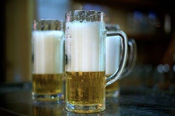 detail of a mug of pils beer with white foam on a brewery table waiting to be filled by the brewmaster