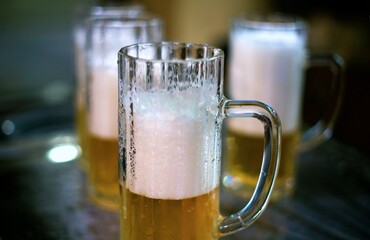detail of a mug of pils beer with white foam on a brewery table waiting to be filled by the brewmaster