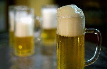 detail of a mug of pils beer with white foam on a brewery table waiting to be filled by the brewmaster