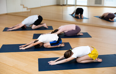 Family of four practicing yoga on mats at gym, concept of families exercising together