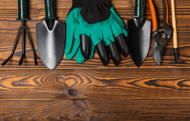 Gardening tools, pruner, gardening gloves, shovel and rake on brown wood. Conceptual composition of...
