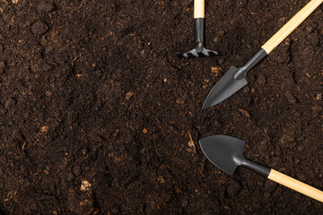 Garden tools on the background of the texture of fertile soil.Garden shovels and rakes. Top view....