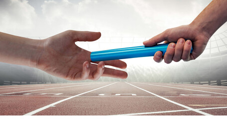 Image of athlete's hands passing relay baton over racing track in sports stadium