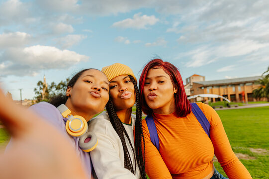 multiracial group of three teenage girl friends using a smartphone to take photos together. classmates and friendship. youth culture and technology
