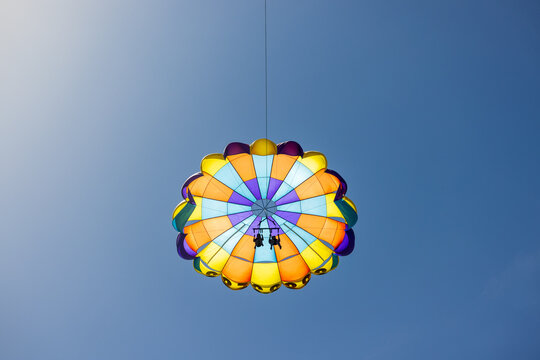 A parasailer floats in the sky with a cloudless blue background