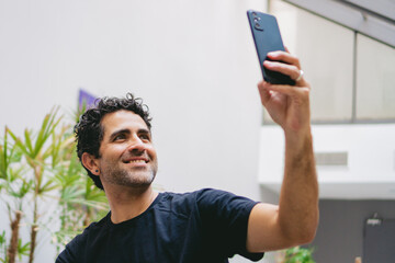 Middle-aged Latin man taking a selfie in the lobby of the hotel where he is staying.