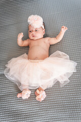 baby girl in tutu and pink ballet slippers lying on a gray blanket © FABIAN PONCE GARCIA