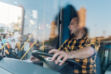 Bus driver behind the wheel of a public transport vehicle - obrazy, fototapety, plakaty