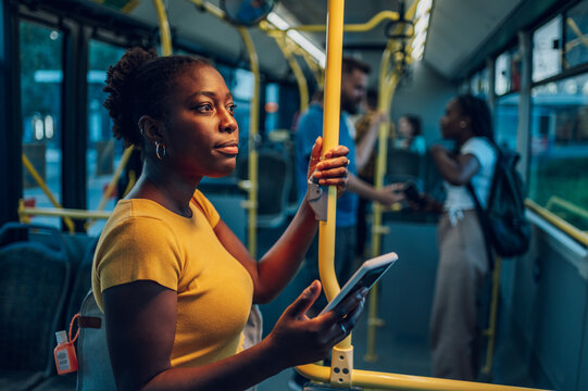 African american woman riding in a bus and using a smartphone during a night