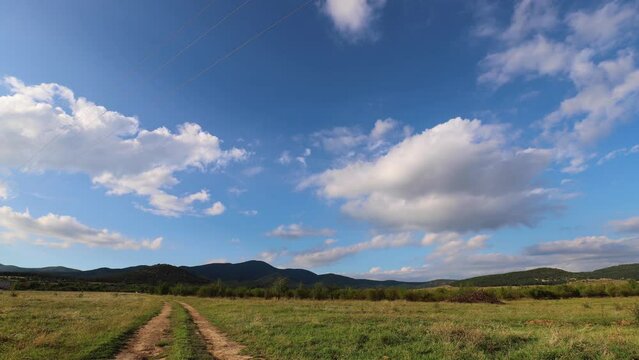 Moving clouds above the country road on the plain and mountain at the horizon.