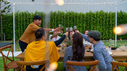 Group of Happy Asian people toasting wine glasses during outdoor celebration dinner party in the...