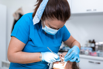 Dentist appointment at a dental clinic, placing braces locks on the teeth and pulling the archwire to fix it