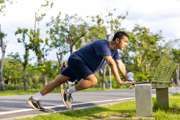 Asian man in sportswear stretching body and warm up before jogging exercise at public park in the...