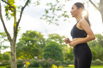 Attractive Asian woman in sportswear jogging exercise at public park in summer morning. Healthy girl athlete enjoy outdoor activity lifestyle sport training fitness running workout in the city.