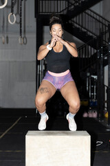 Fototapeta na wymiar latin Woman doing box jumps at crossfire gym