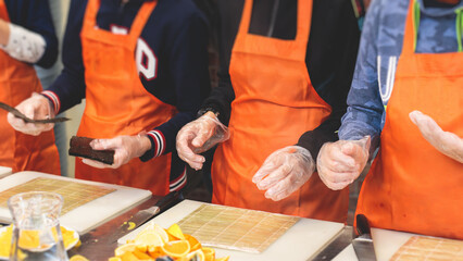 Group of children in a cooking class, kids preparing asian style food in the kitchen together, kids in aprons learn cooking on master class, chef uniform, hands in gloves