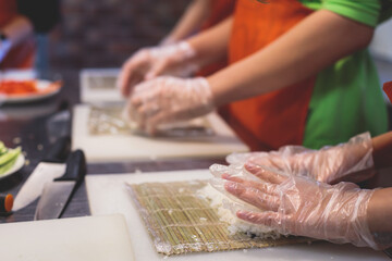 Group of children in a cooking class, kids preparing asian style food in the kitchen together, kids in aprons learn cooking on master class, chef uniform, hands in gloves