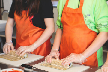 Group of children in a cooking class, kids preparing asian style food in the kitchen together, kids...