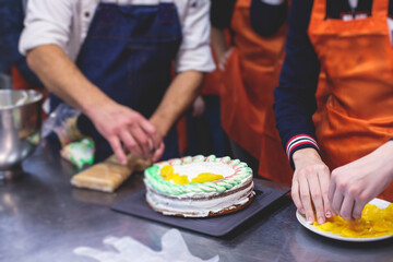 Group of children in a cooking class, kids preparing asian style food in the kitchen together, kids in aprons learn cooking on master class, chef uniform, hands in gloves