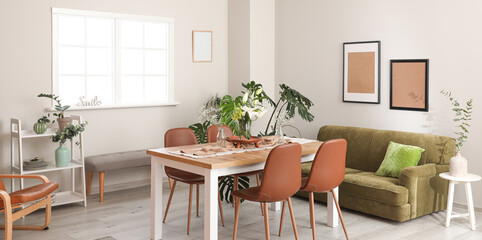 Interior of modern light dining room with big table and green sofa
