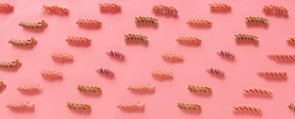 Dry fusilli pasta on pink background. Pattern for design