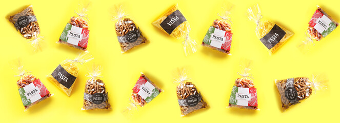 Bags with uncooked Italian pasta on yellow background. Pattern for design