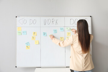 Young businesswoman near scrum task board in office, back view