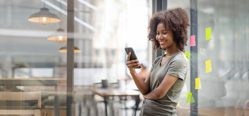 A black American african business woman in afro hairstyle planning in meeting at office and use post it notes to share idea. Brainstorming concept. Sticky note on glass wall.