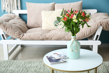 Fototapeta na wymiar Cozy armchair and vase with alstroemeria flowers on table in interior of living room