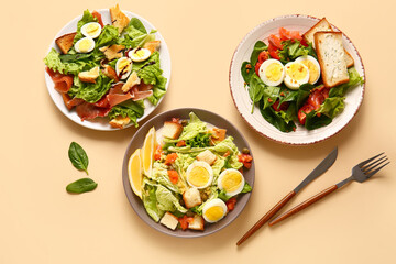 Plates of delicious salads with boiled eggs on beige background