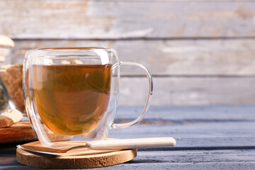 Glass cup of hot green tea on color wooden table