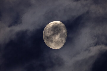 Fototapeta na wymiar The moon and tiny Jupiter pass through the clouds.