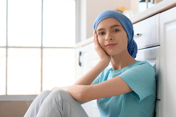 Teenage girl after chemotherapy sitting in kitchen