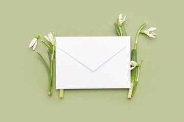 Beautiful snowdrops and envelope on green background