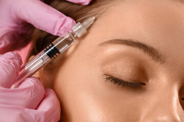 Young woman receiving filler injection in face, closeup