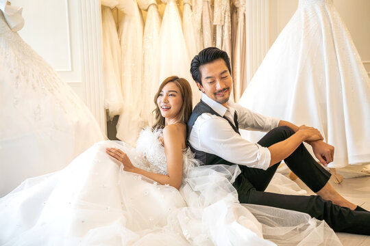 Portrait of smiling cheerful happy love asian couple fashion bride man and woman posing in white wedding dress for pre wedding hug together at wedding interior fashion studio
