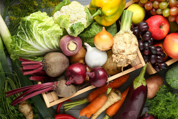 Different fresh vegetables and fruits with crate on grey wooden table, top view. Farmer harvesting