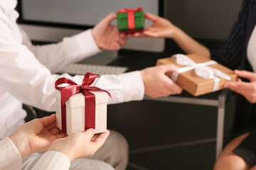 Colleagues presenting gifts each other in office, closeup. Space for text