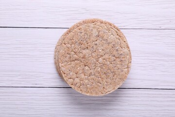 Fresh crunchy crispbreads on white wooden table, top view