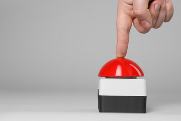 Man pressing red button of nuclear weapon on light gray background, closeup with space for text....