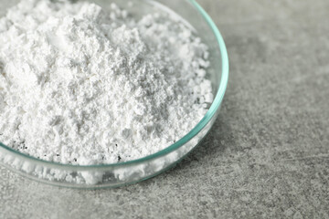 Petri dish with calcium carbonate powder on light grey table, closeup