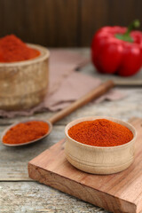 Bowl with aromatic paprika powder on old wooden table