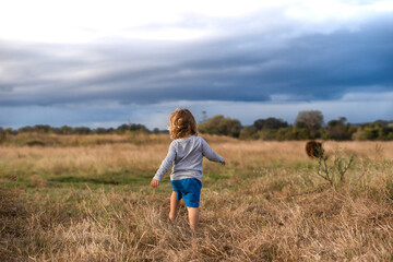 Naklejka na ściany i meble Toddler running through farmland
