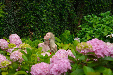 blonde woman looking at green vines and flowers