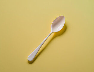 Realistic white plastic spoon isolated on yellow background. Generative AI