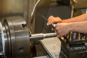 Close up scene the machine operator measuring outside diameter metal shaft parts by dial Vernier...