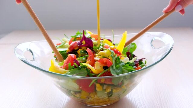 Pouring salad vinaigrette in bowl of healthy vegetable salad. Dressing salad. High quality 4k footage