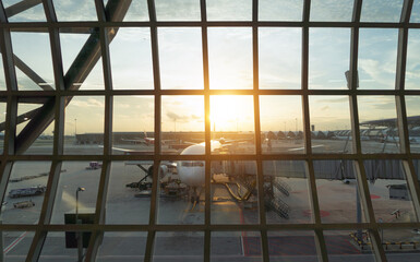 An airplane jet with buildings window view in urban city from terminal gate in the airport. Traveling and transportation concept on holiday vacation.