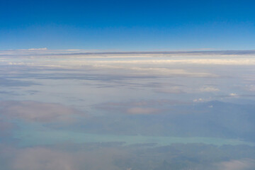 Airplane jet flying above clouds view with blue sky from the window in traveling and transportation concept. Nature landscape background.