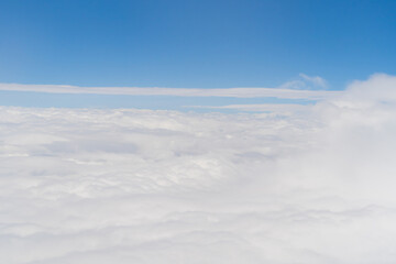 Fototapeta premium Airplane jet flying above clouds view with blue sky from the window in traveling and transportation concept. Nature landscape background.